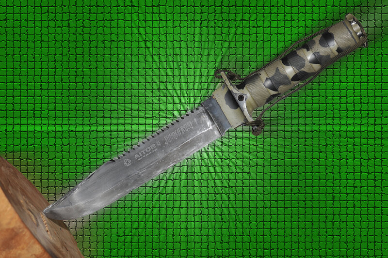 A combat knife on a green mesh