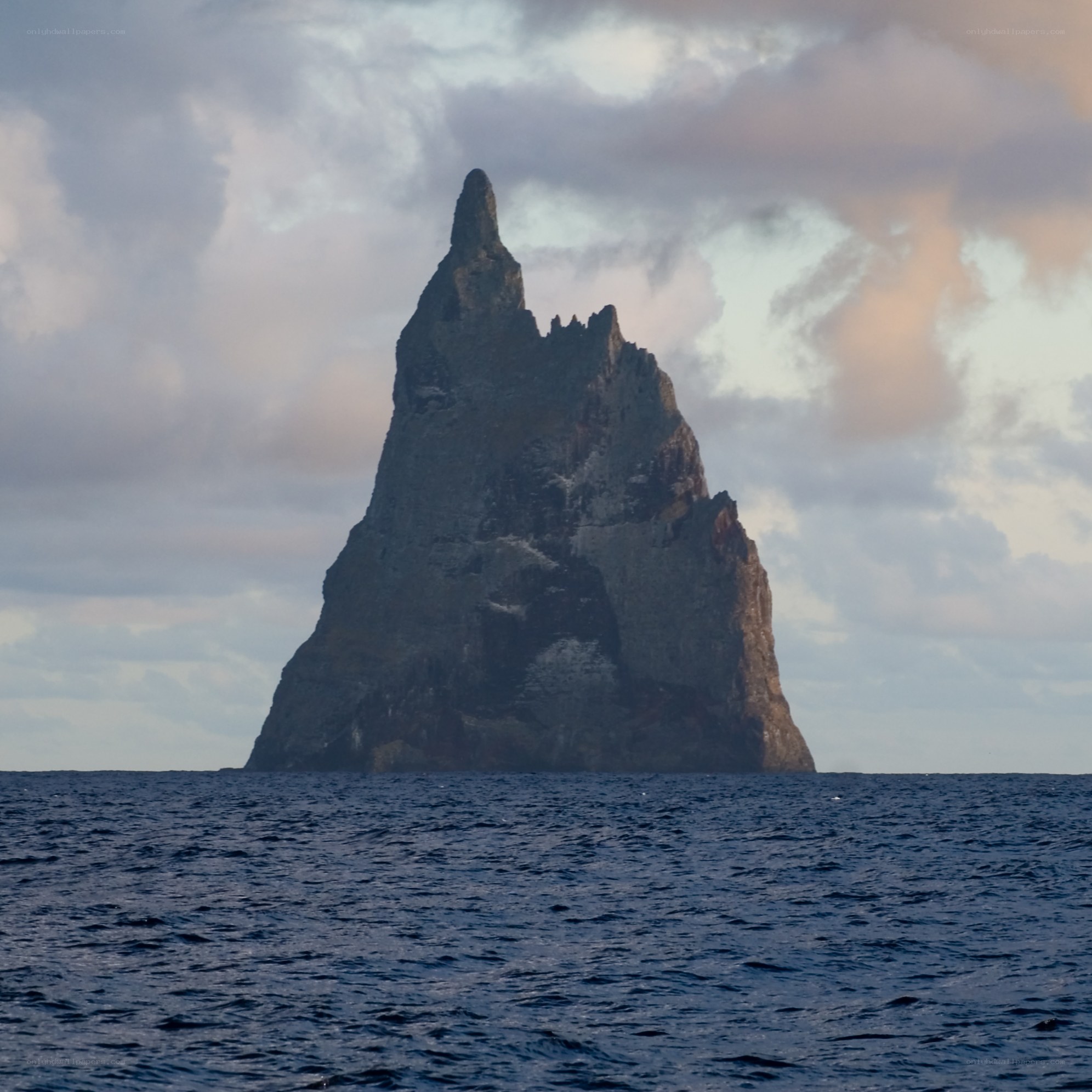 A lone sea stack rises from the ocean
