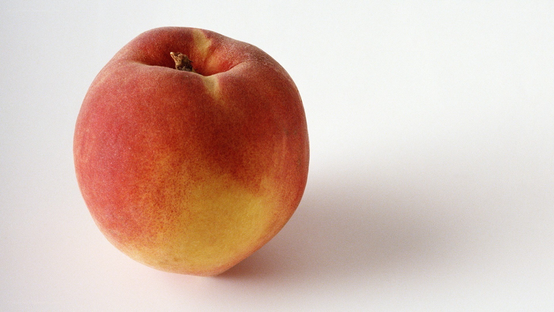 a ripe peach on a white surface