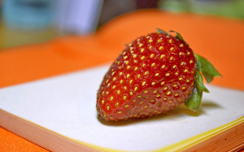 a single strawberry on a plate