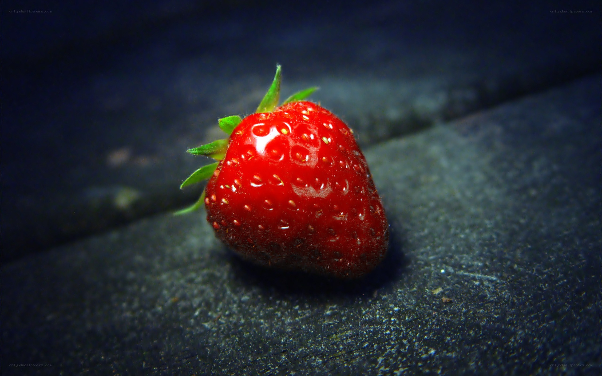 a single strawberry on dark surface