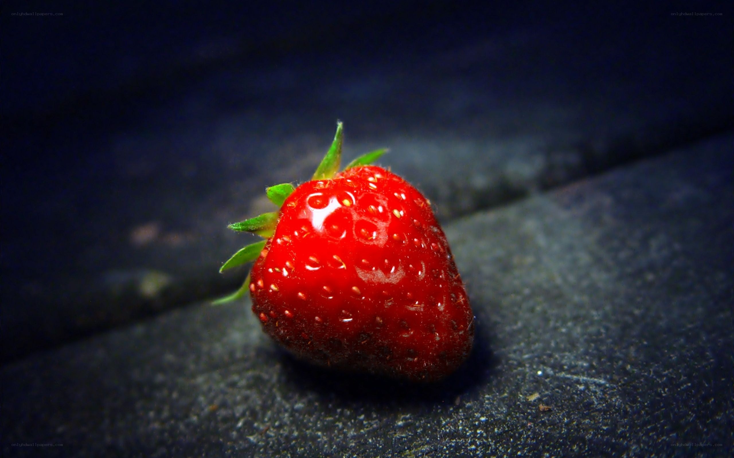a single strawberry on dark surface