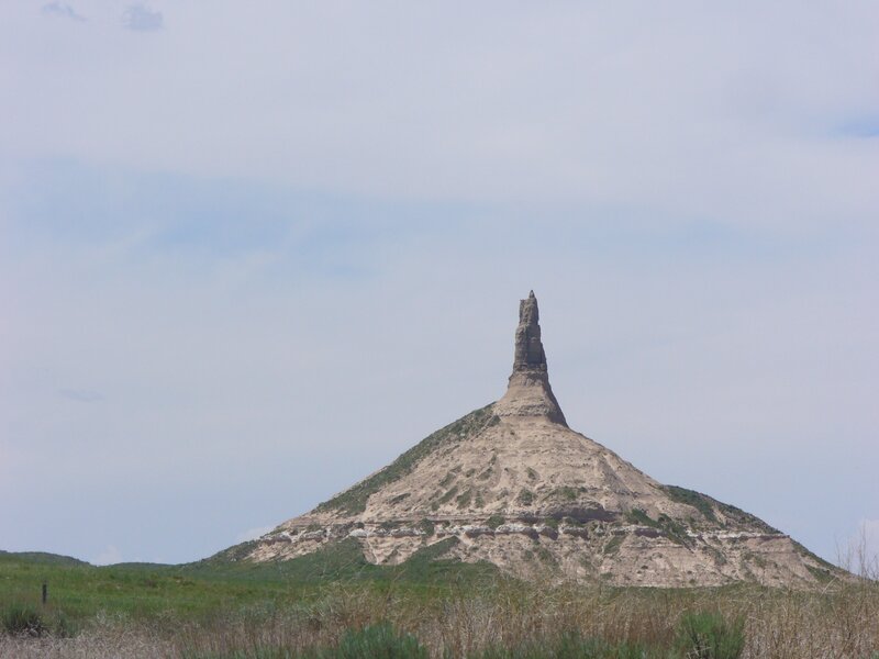 A tall rock spire rises from a hill