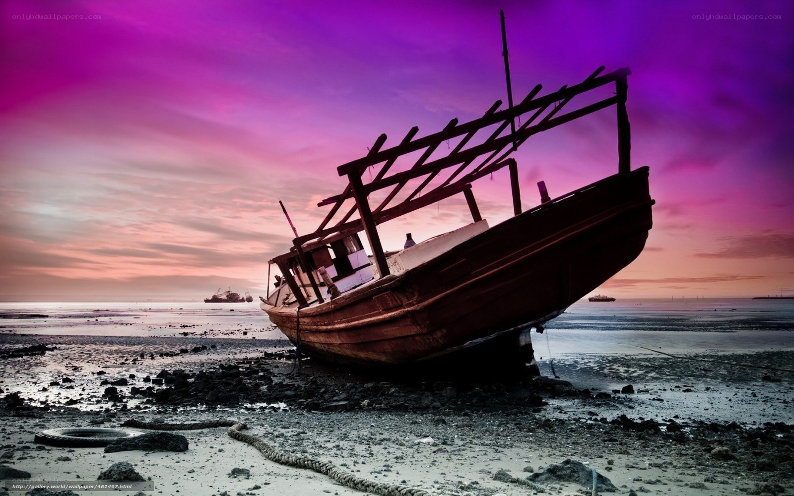 Abandoned boat on beach at sunset