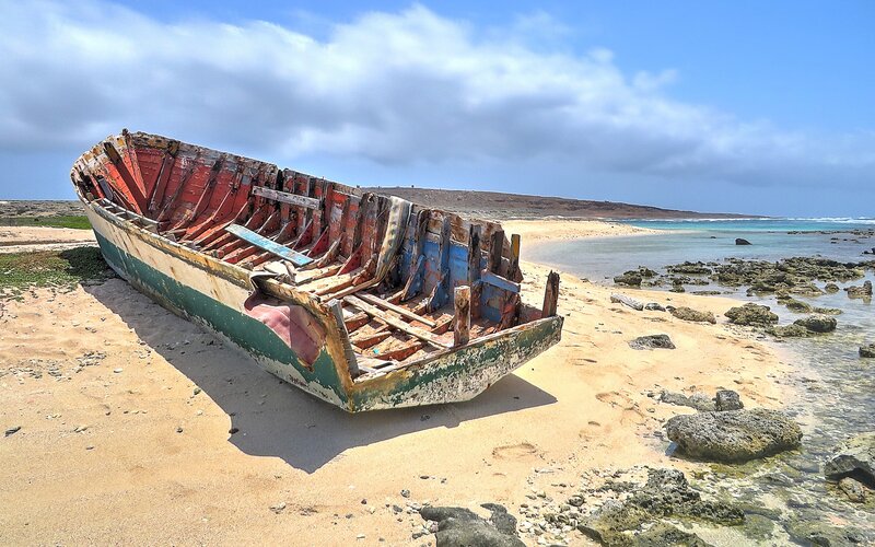 Abandoned Boat on Beach — Blue, Serene, Afternoon, Photograph, Ocean, Rocks
