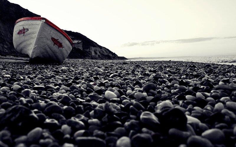 Abandoned boat on pebble beach
