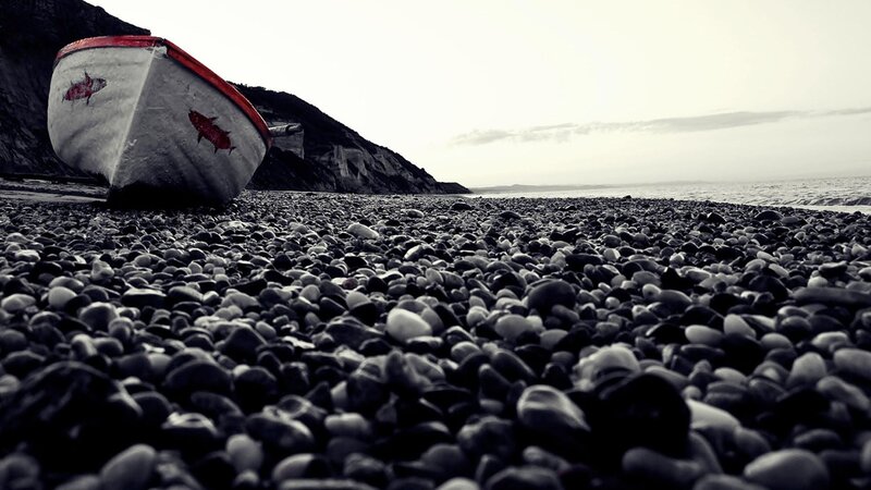 abandoned boat on pebble beach