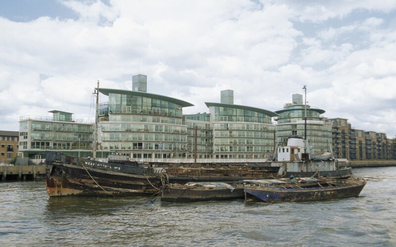 abandoned boats near modern buildings