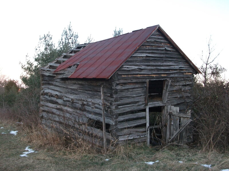 Abandoned log cabin in field