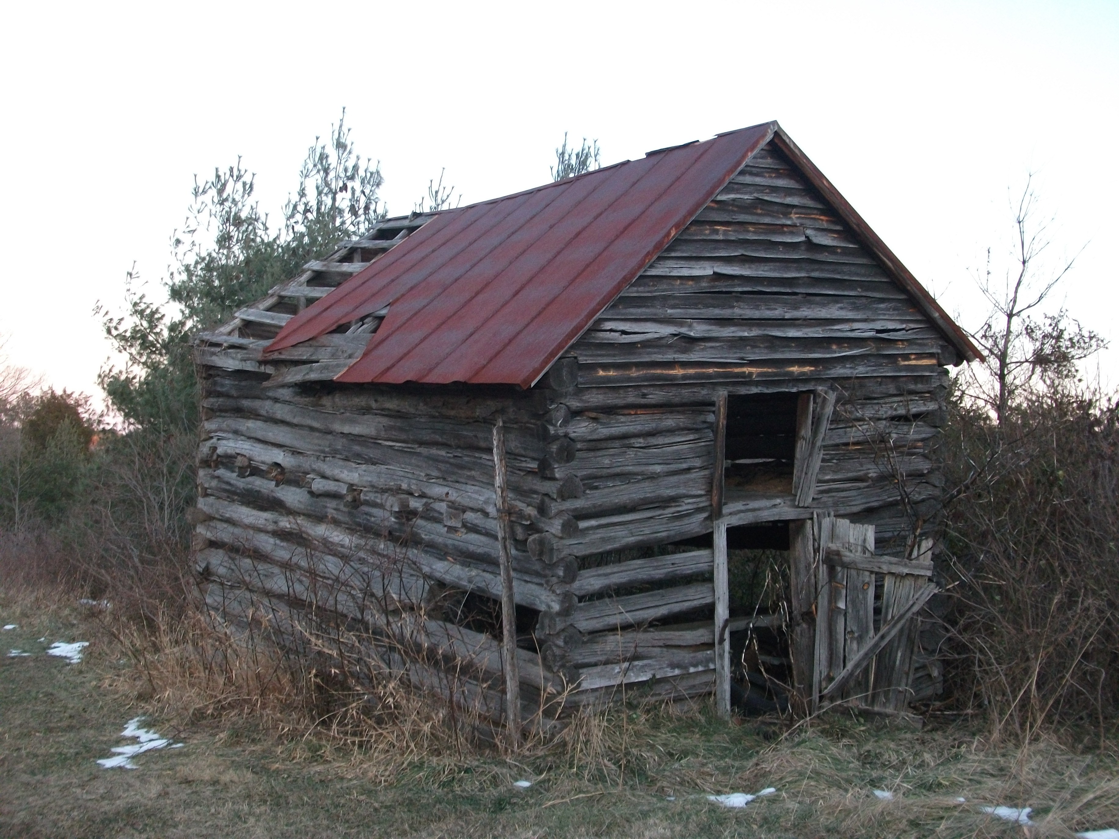 Abandoned log cabin in field