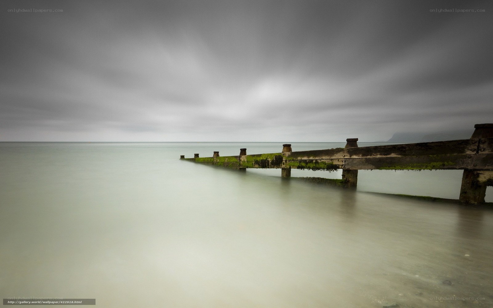 Abandoned pier under cloudy sky