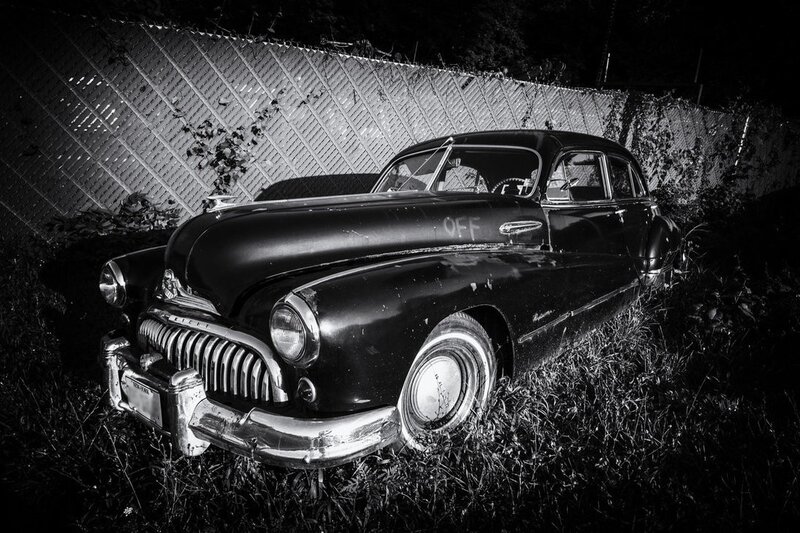Abandoned vintage car in overgrown yard