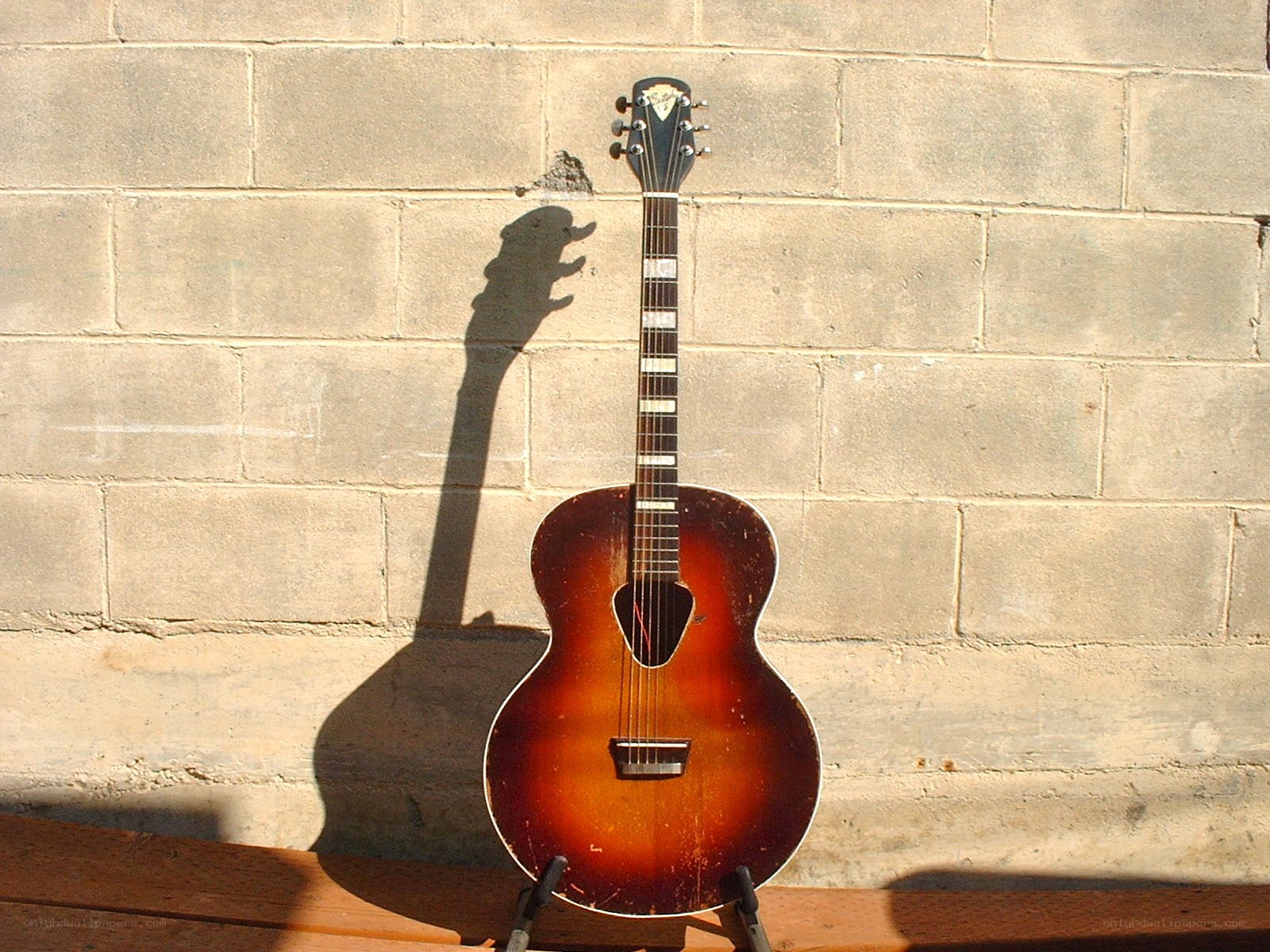 acoustic guitar against brick wall
