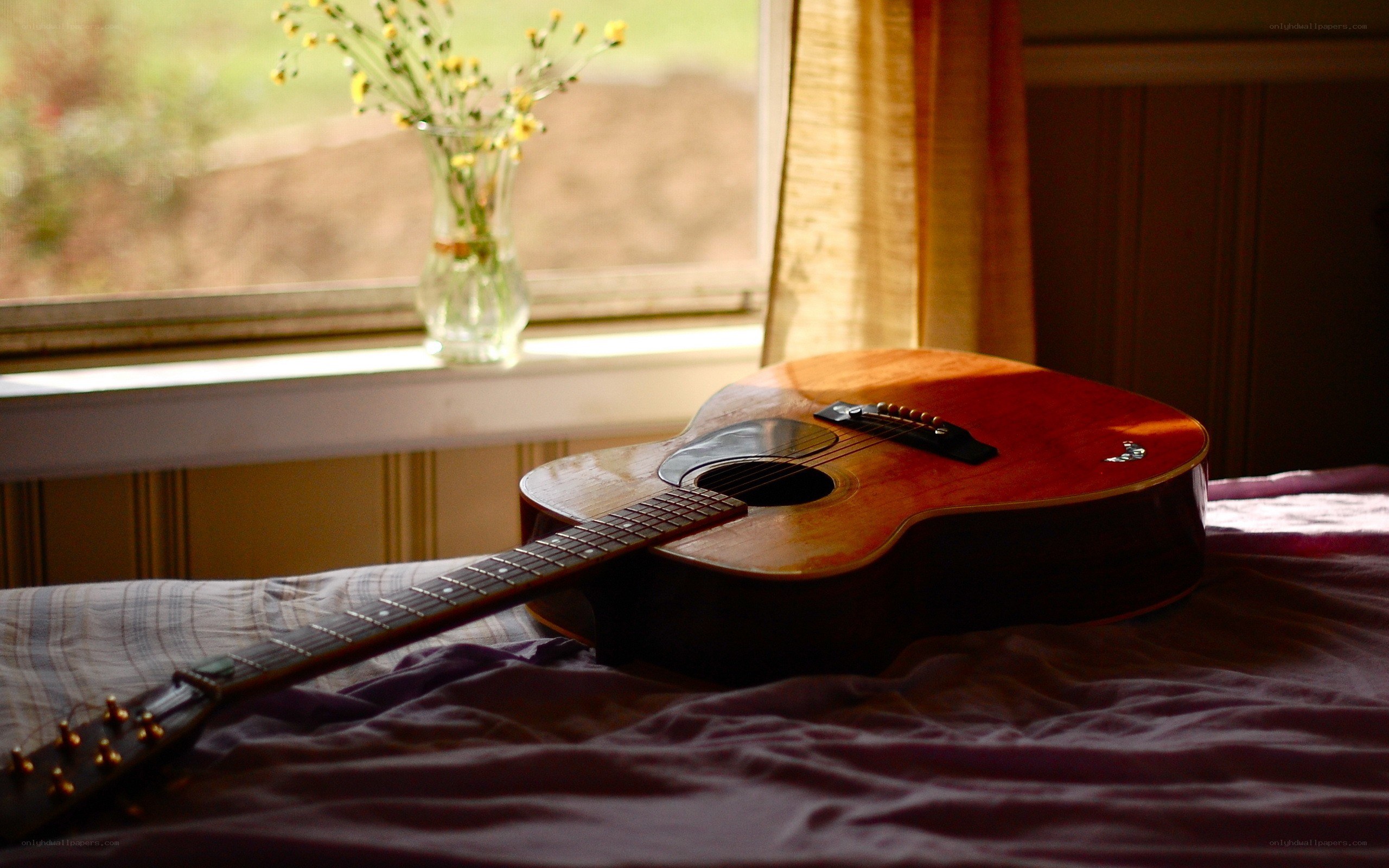 Acoustic guitar on a bed