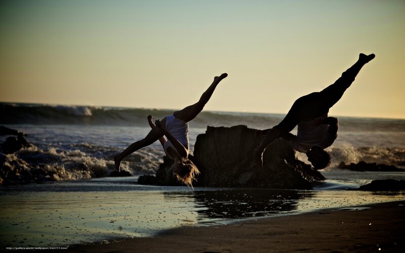 Acrobats on the beach at sunset