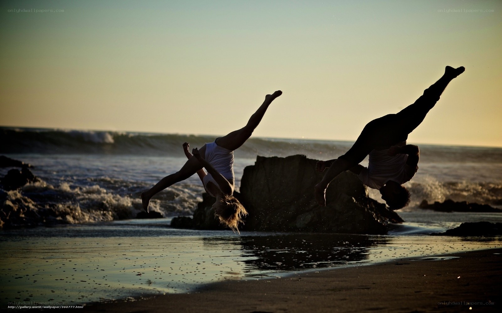 Acrobats on the beach at sunset