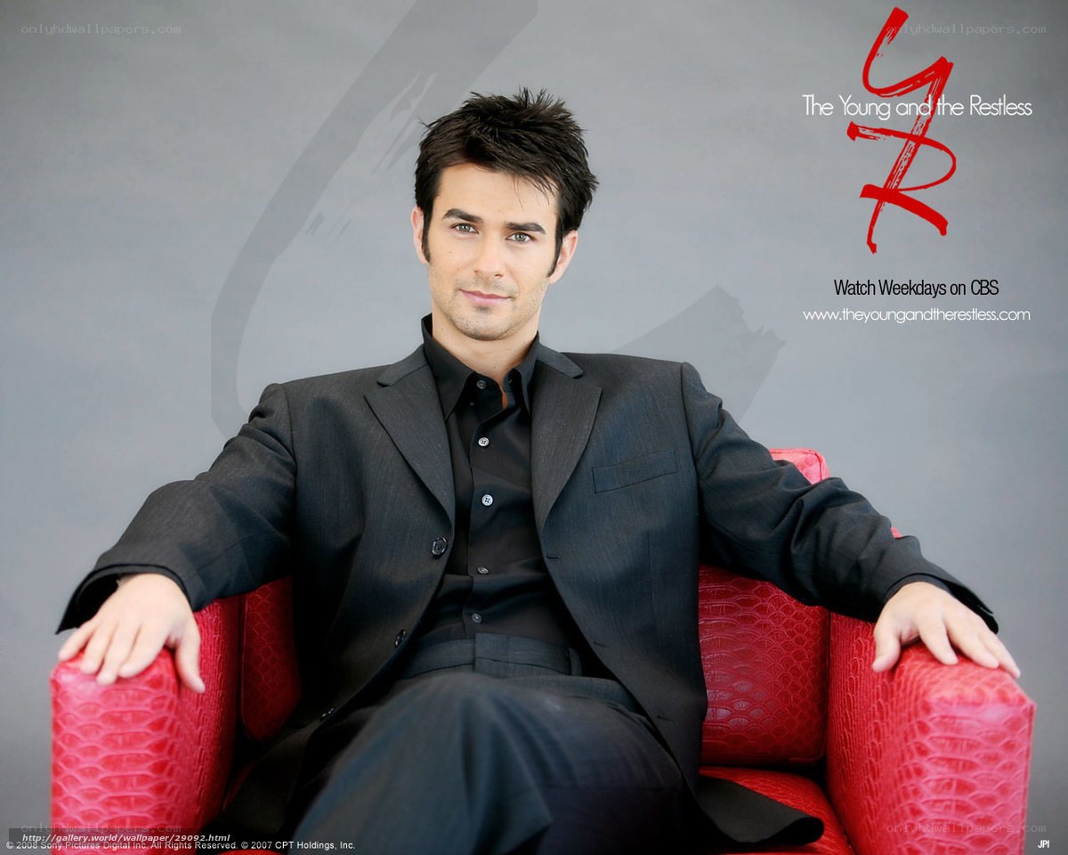 actor in black suit on red chair