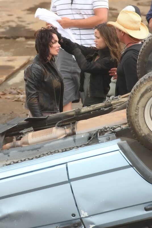Actors on film set with overturned car
