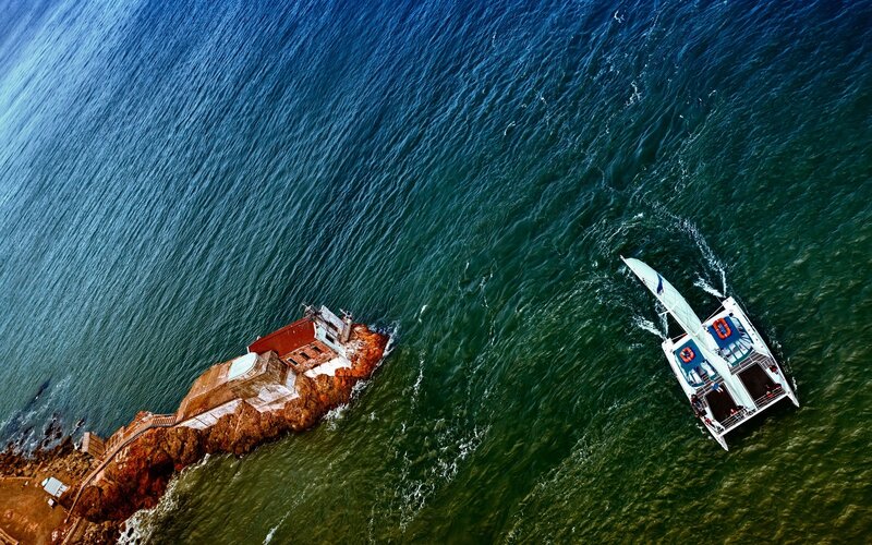 Aerial view of catamaran near lighthouse