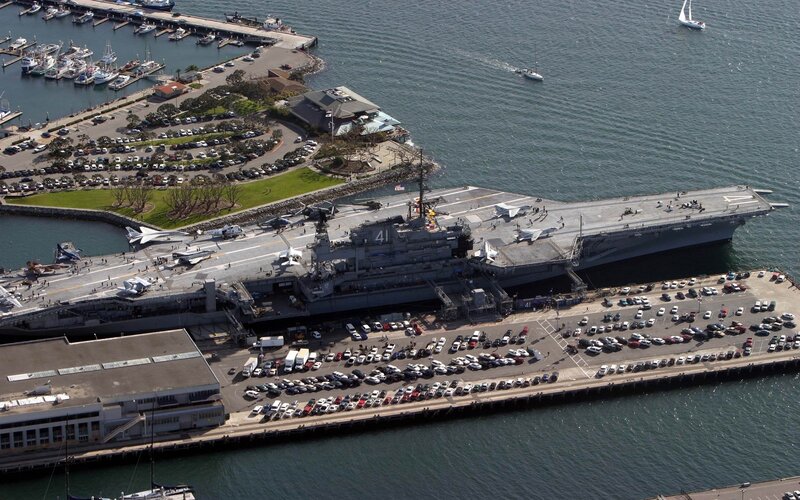 Aircraft Carrier in Harbor — Gray, Calm, Afternoon, Photograph, Parking Lot, Boats