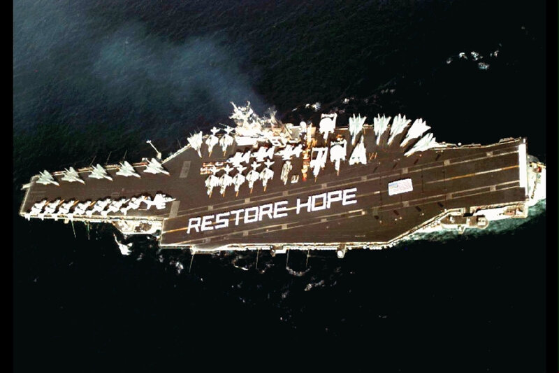 Aircraft carrier with 'RESTORE HOPE' text