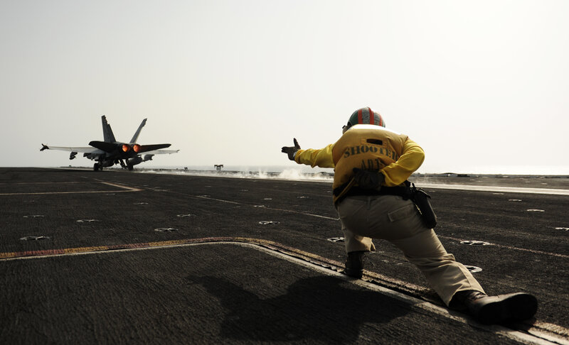 Aircrew directing jet on aircraft carrier