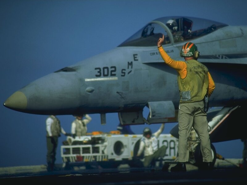 Aircrew preparing fighter jet on aircraft carrier
