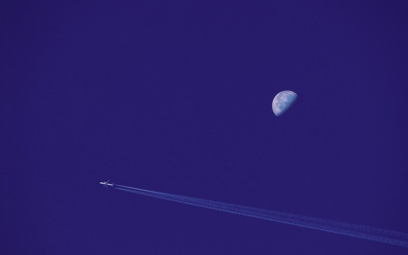 Airplane and moon in blue sky