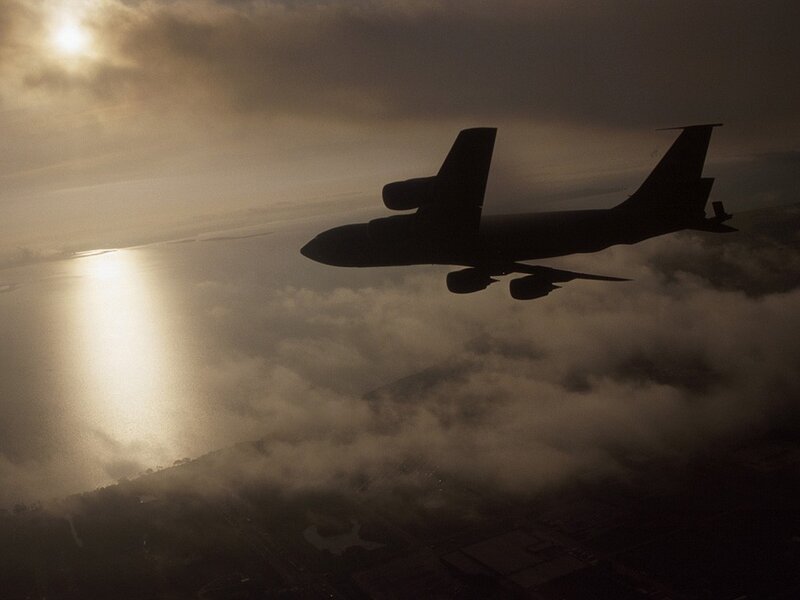 Airplane flying above clouds at sunset