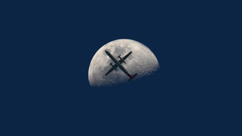 Airplane flying in front of the moon