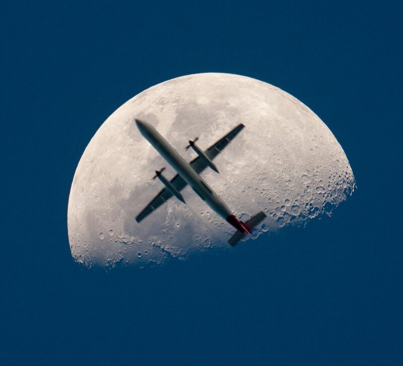 Airplane flying in front of the moon