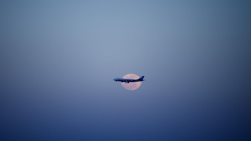 Airplane flying in front of the moon