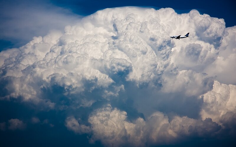 Airplane flying near a large cloud