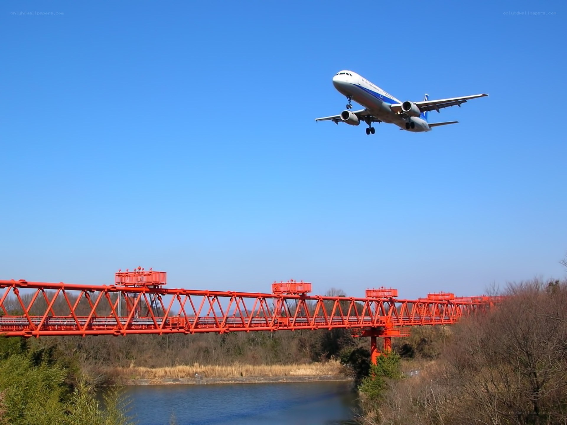 Airplane flying over a red bridge