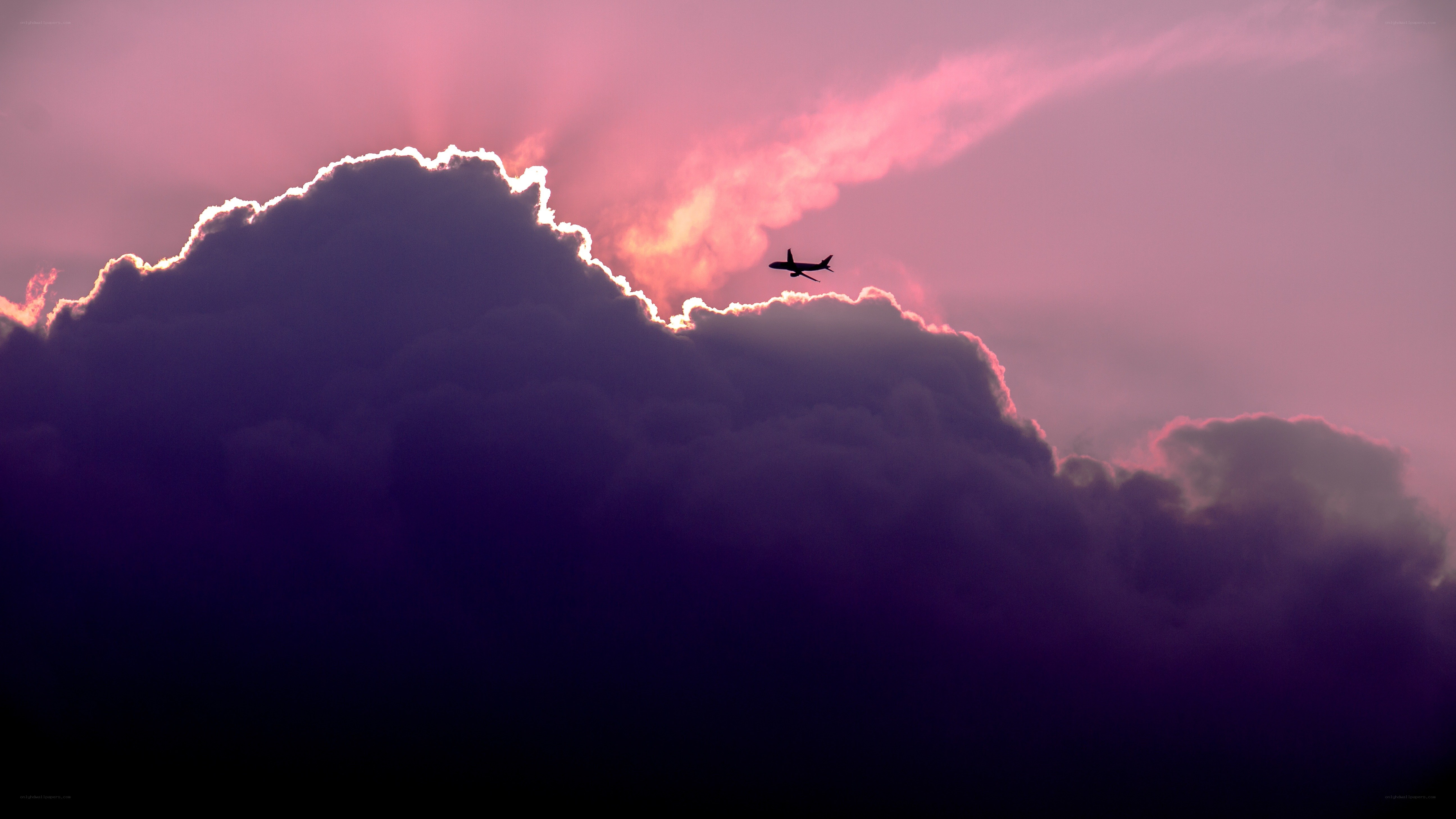 Airplane flying over clouds at sunset