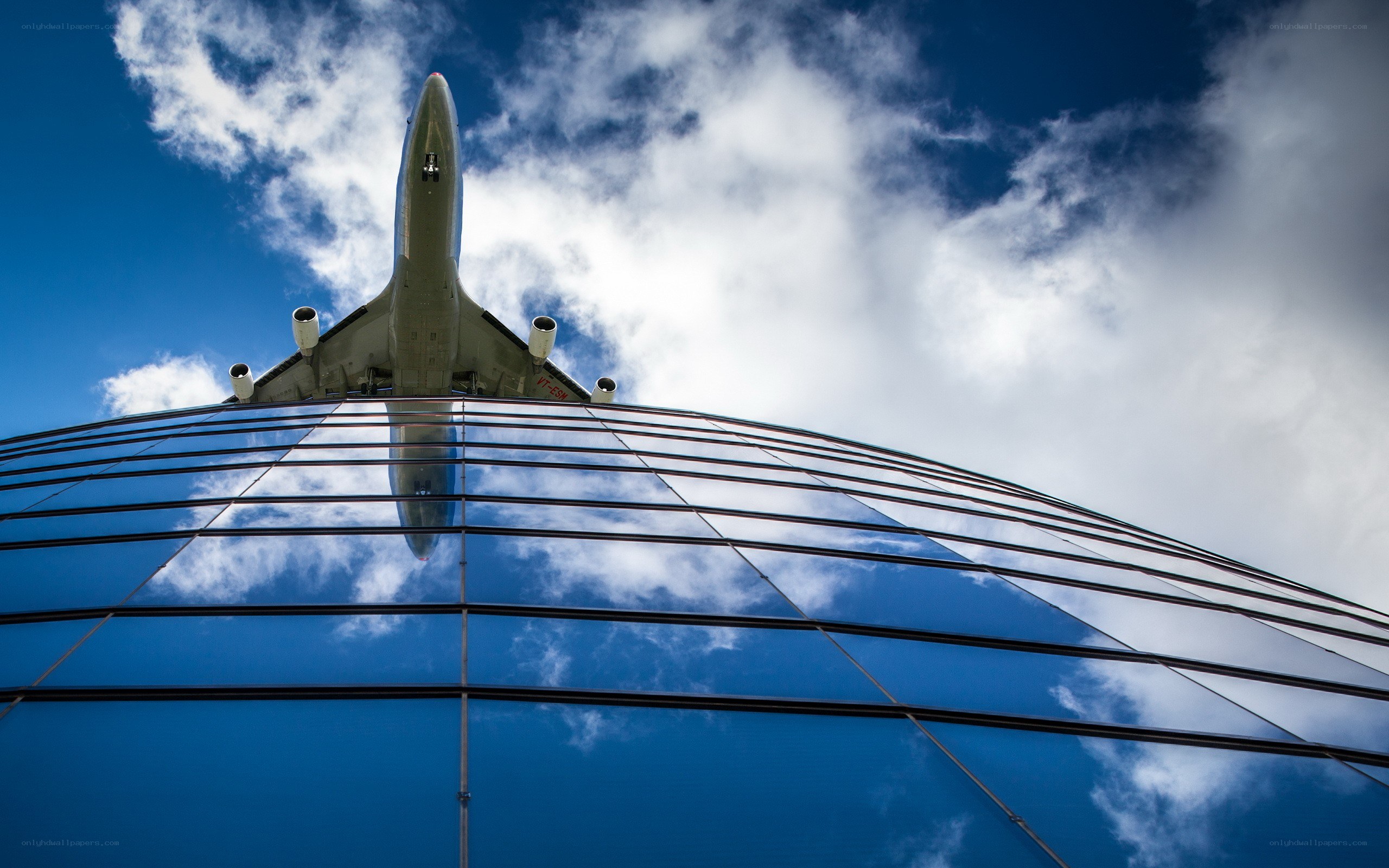 Airplane flying over glass building