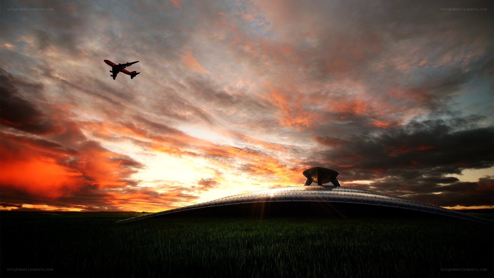 Airplane flying over modern building at sunset