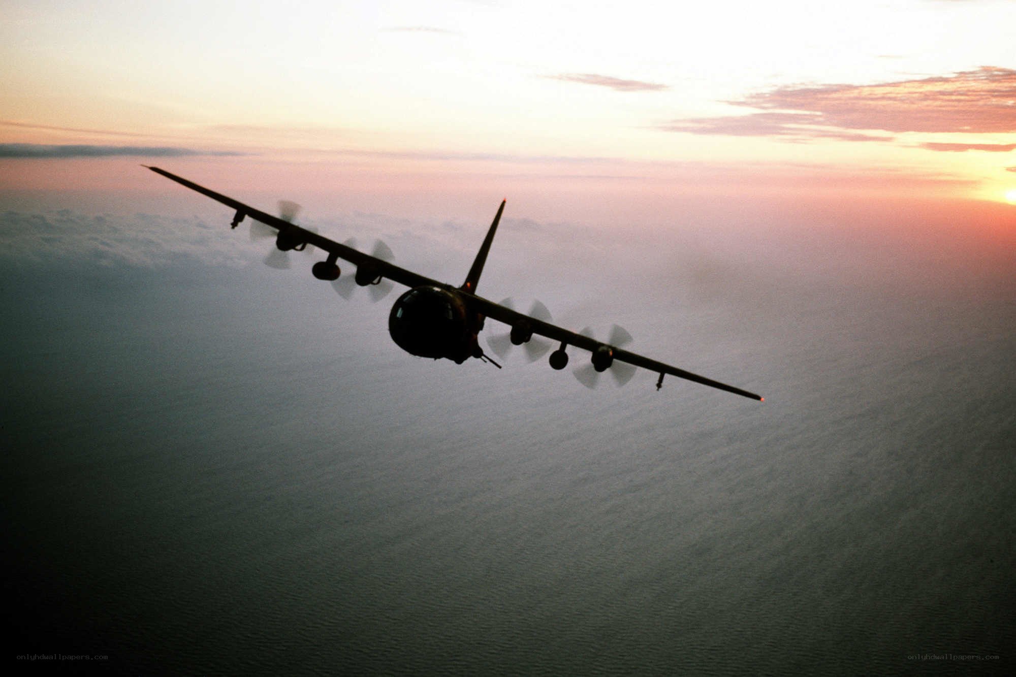 Airplane flying over ocean at sunset