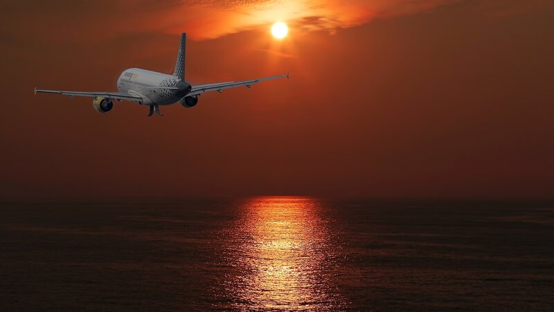 Airplane Flying over Ocean — Orange