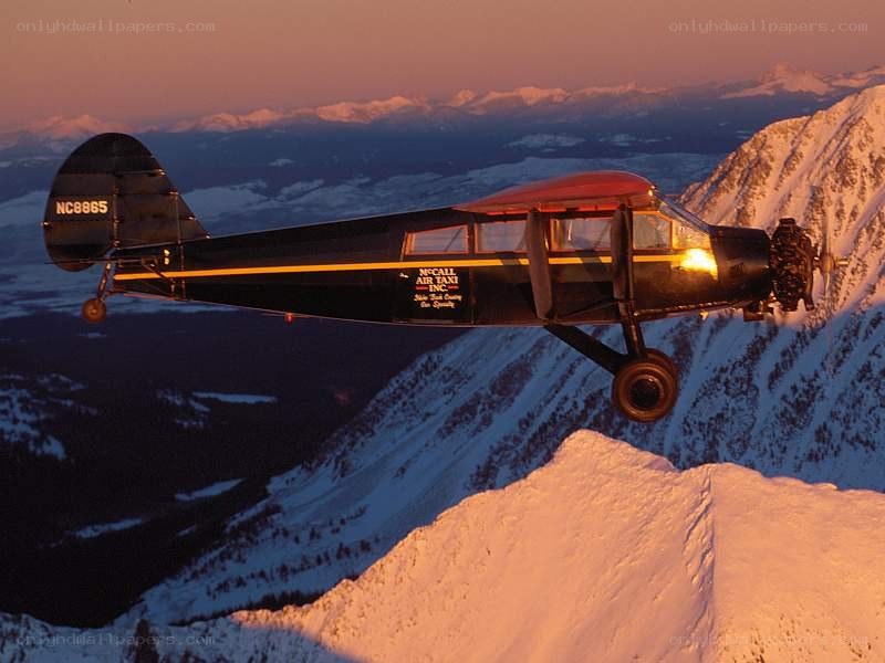 Airplane flying over snowy mountains