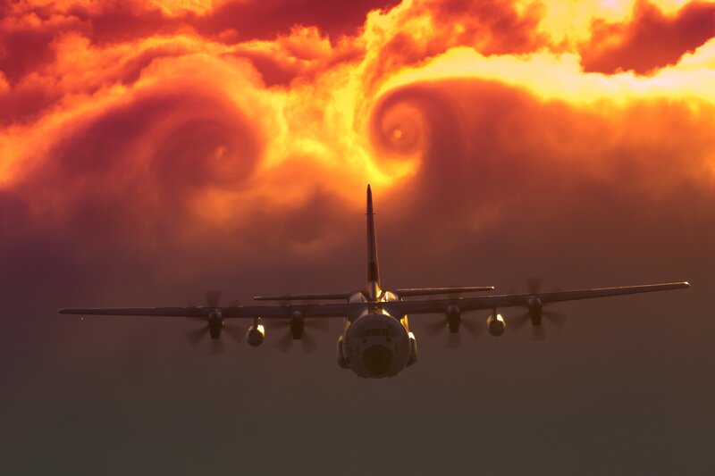 Airplane flying through sunset clouds