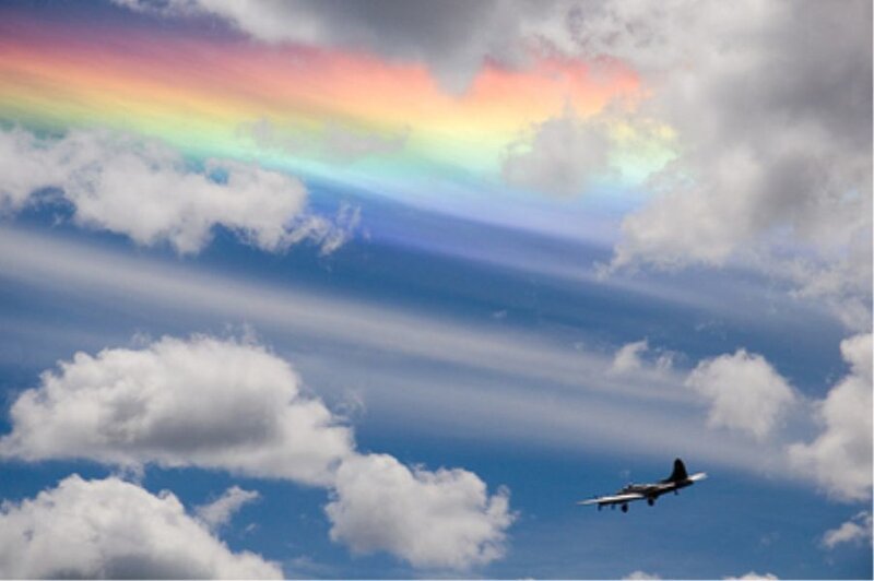 Airplane flying under rainbow