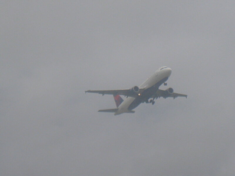 Airplane in Cloudy Sky — Gray