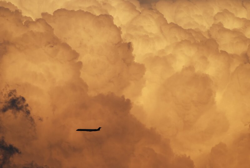 Airplane in Cloudy Sky — Orange