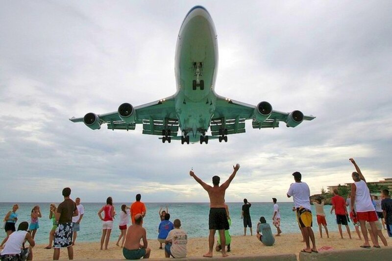 Airplane landing over beach crowd