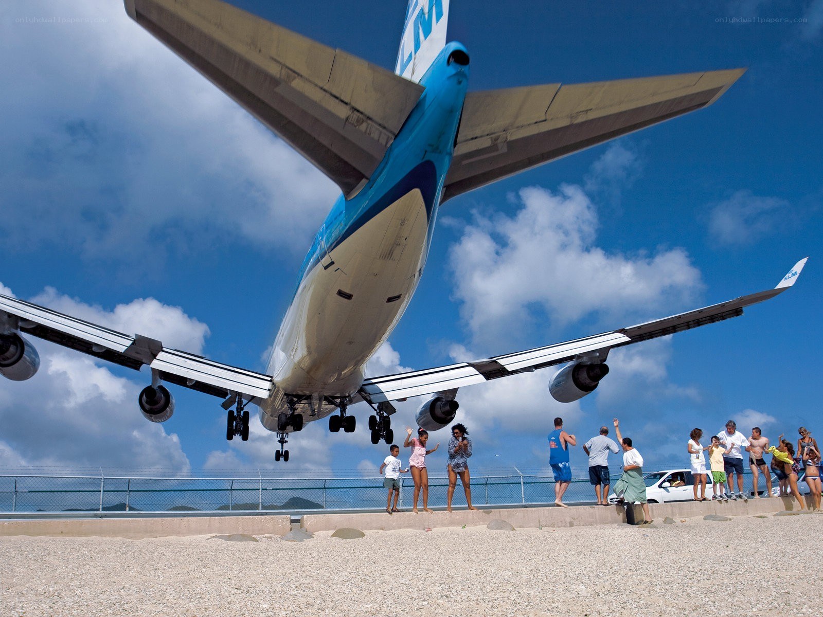 Airplane landing over beach crowd