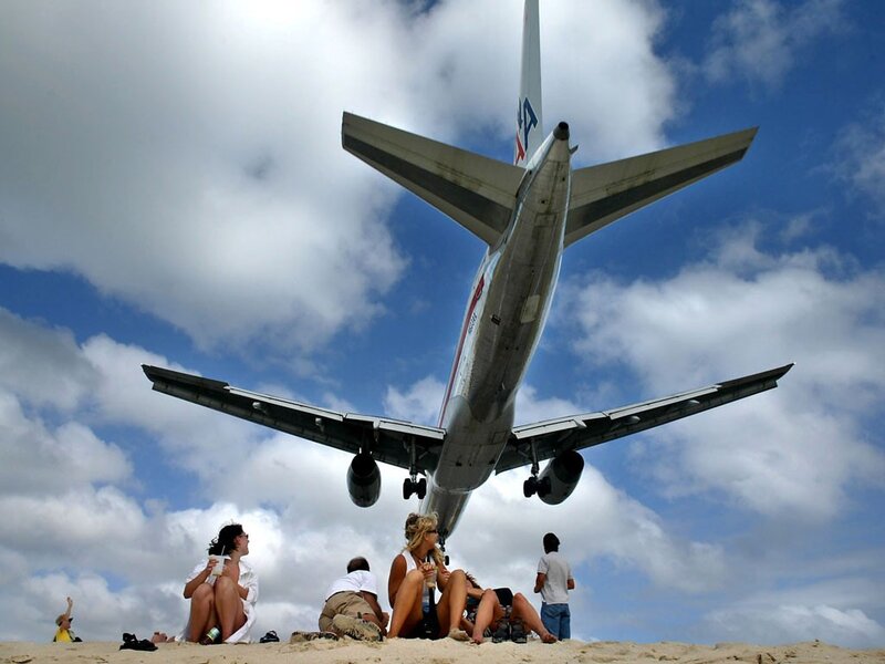 Airplane landing over beachgoers