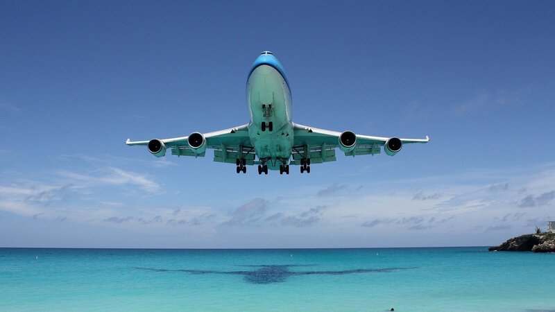 Airplane landing over turquoise sea