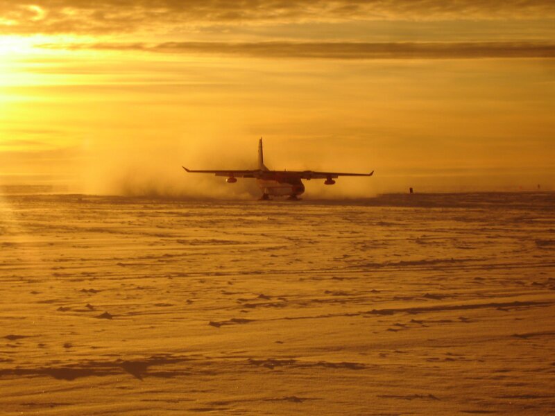 Airplane on snowy runway at sunset