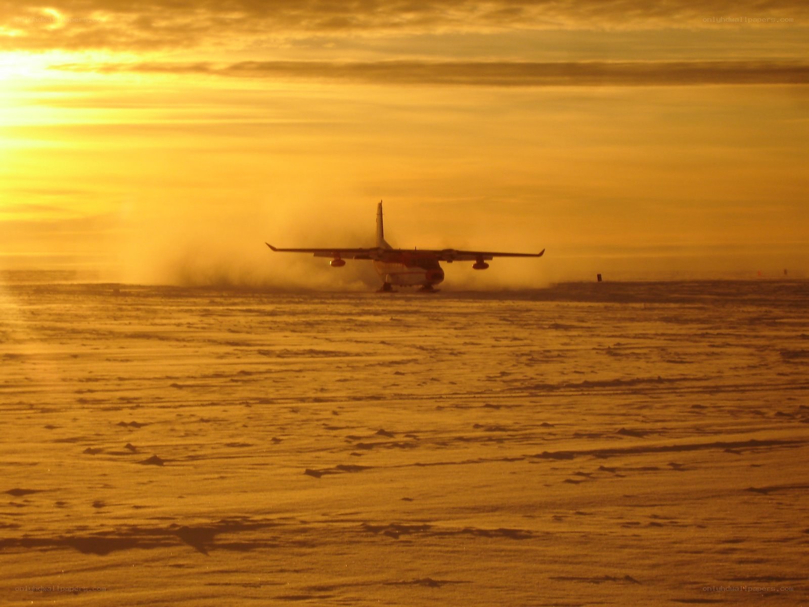 Airplane on snowy runway at sunset